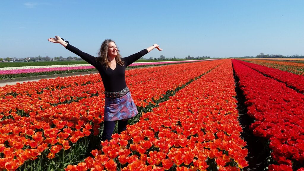 Woman standing with arms outstretched in field of red tulips